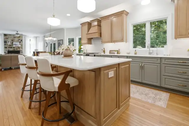 Martinsburg, WV kitchen island in Wicker finish with upholstered stools, green base cabinets and quartz top