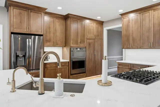 Harpers Ferry, WV kitchen remodel with walnut-tone Shaker cabinets, white quartz counters, brass faucet and gas cooktop