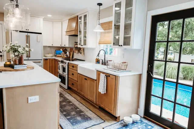 Falling Waters, WV kitchen with white glass-front uppers, wood base cabinets, farmhouse sink and a glass door looking out to the pool