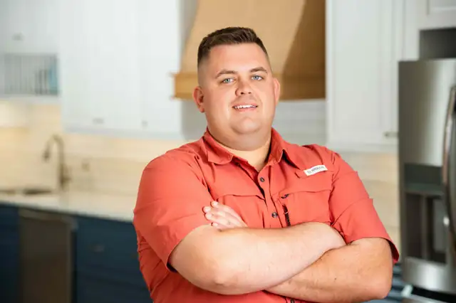 Owner Ben DeOms standing with arms crossed in a kitchen display
