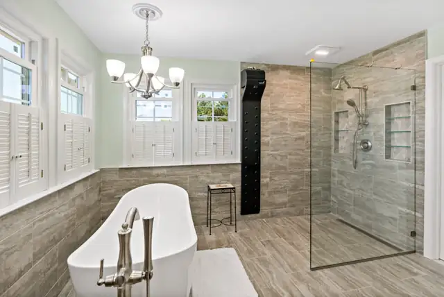 Primary bathroom remodel with freestanding white soaking tub, wood-look tile wainscot and frameless glass walk-in shower