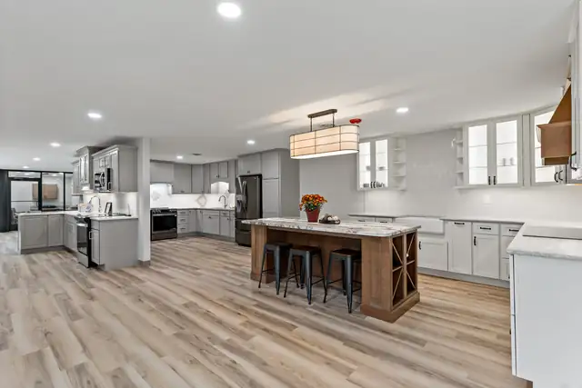 Cottage-style kitchen with white cabinets, open wood shelves, wood range hood, butcher block island and retro green refrigerator