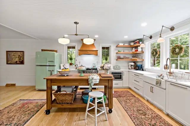 Large kitchen with dark wood island, built-in wine fridge, white quartz top, glass-front uppers and pendant lights