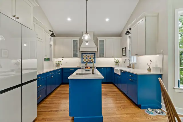 Kitchen remodel with bright blue base cabinets and island, white uppers, patterned tile backsplash and white range hood